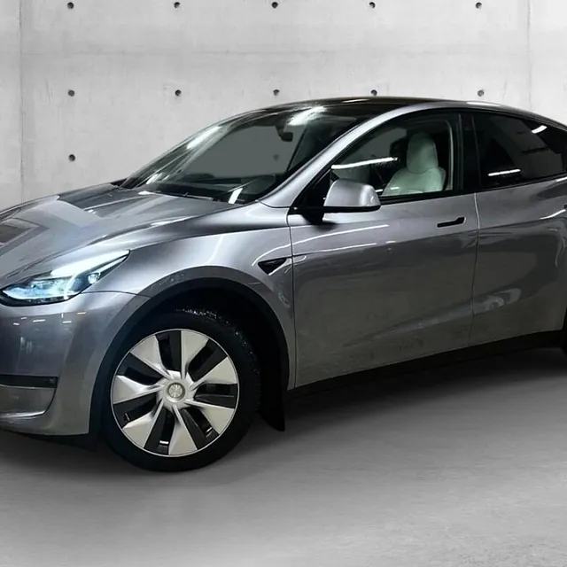 Grå Tesla Model Y elbil i studio, med høy bakkeklaring og stilrent, aerodynamisk design